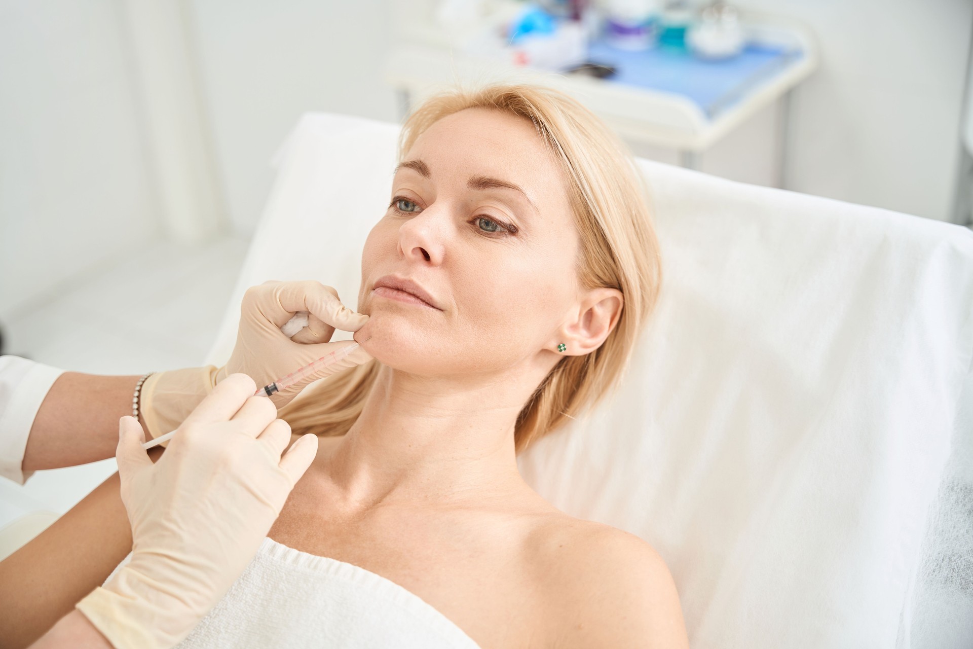 Dermatocosmetologist making injections of hyaluronic acid into the client's chin